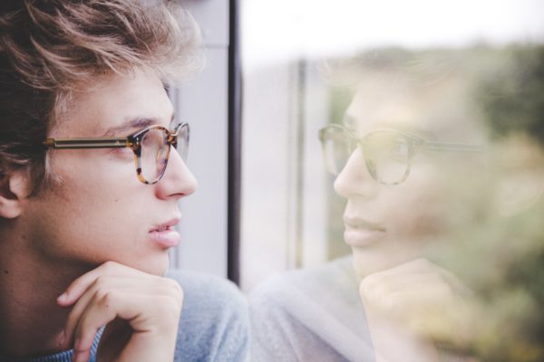 A person looking at his reflection in a glass window