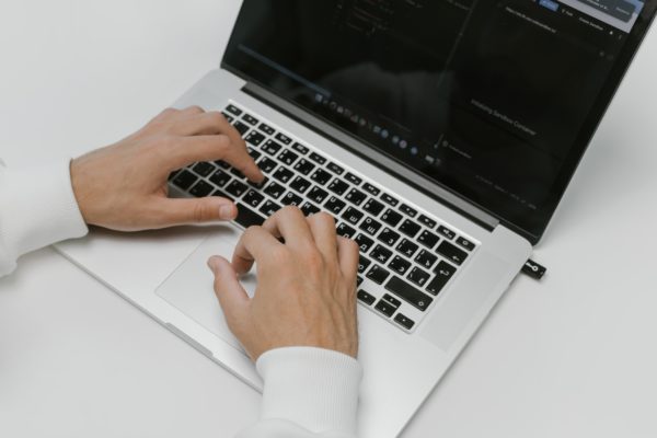 A persons hands working on a laptop