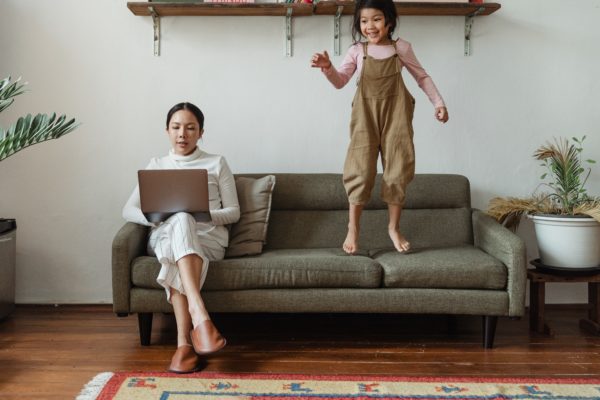 A seated woman working on a laptop with her daughter